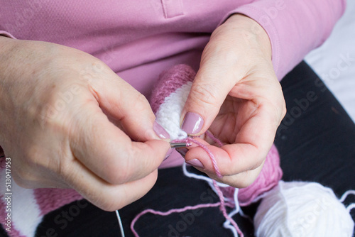 Process of yarn knitting by elderey woman: arms, spins, thread - closeup