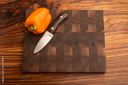 Handmade knife and orange pepper on end grain walnut cutting board cutting board