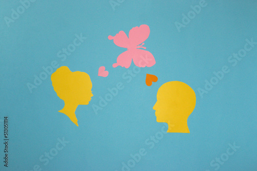 man and woman paper head, woman sends love to man brought by paper pink butterfly, pastel blue background, creative art design, romantic scene photo
