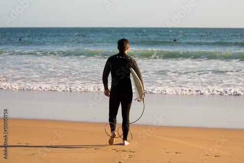 Man surfer with surfboard going to surf at seaside in Carcavelos, Cascais, Portugal