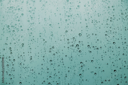 Blue raindrops on glass, abstract liquid texture.