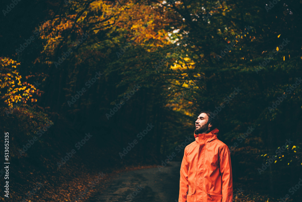 Man wearing orange raincoat in the park at rainy autumn day. Man wearing orange raincoat in the park at rainy autumn day.