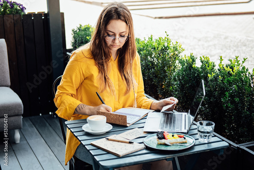 Valokuva Modern astrologer numerologist woman working and writing in notepad numbers