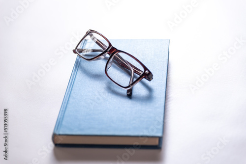  blue study book and magnifying glasses, copy space, reading, myopic eyesight, education concept, selective focus
