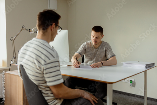 Serious professional man consulting client in office. Two mens having meeting, making business conversation. Insurer giving advice, manager making offer. Mentor teaching intern. Job interview.