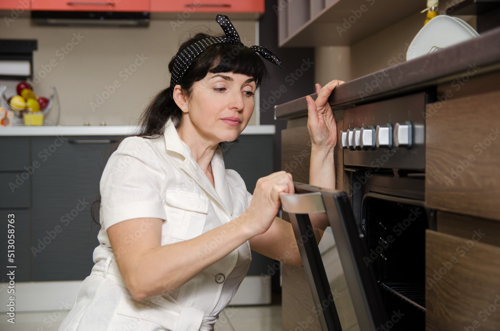 A woman opens the oven to get baked goods out of the oven. A woman opens the oven to get baked goods out of the oven.