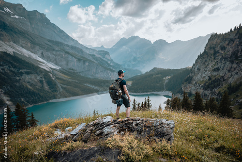 Un homme randonneur qui est en montagne lors d'une randonnée et qui regarde le magnifique panorama, avec un lac, des chemins et une forêt. © Kevin