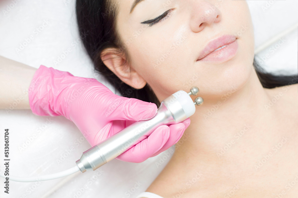 A young woman is lying on the RF-lifting procedure for face skin tightening and face contour correction. Close-up. A young woman is lying on the RF-lifting procedure for face skin tightening and face contour correction. Close-up.
