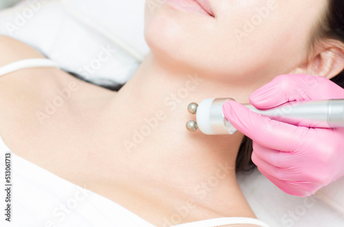 A young woman is lying on the RF-lifting procedure for face skin tightening and face contour correction. Close-up.