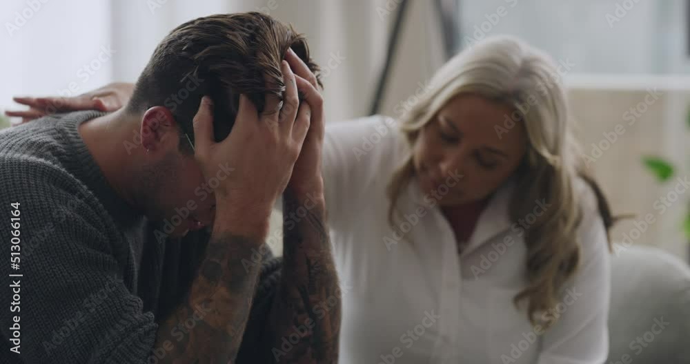 Man crying and being comforted by psychologist during therapy. Upset and anxious man with his head in his hands and sharing trauma story with mature therapist. Stressed and seeking mental health help