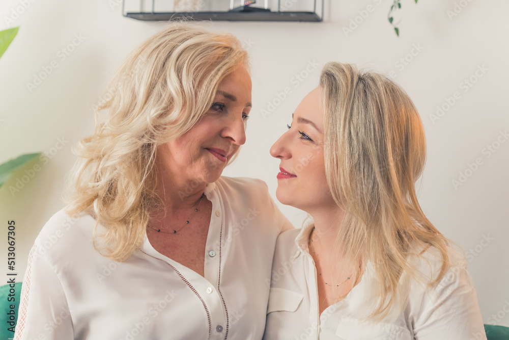 Happy elegant millenial blonde ladies sitting toghether, hugging and looking at each other with love and affection. High quality photo Happy elegant millenial blonde ladies sitting toghether, hugging and looking at each other with love and affection. High quality photo