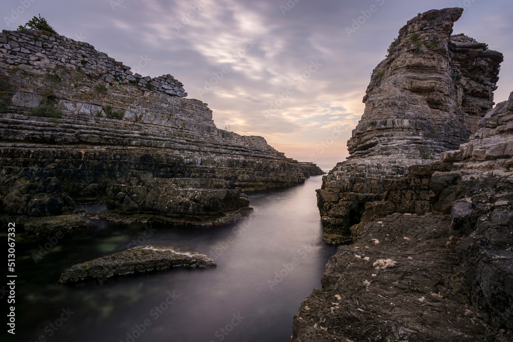 rock formations at seaside and colorful sunset with clouds
