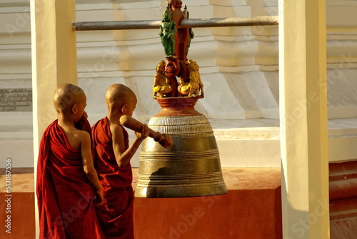 Young monks ringing a bell in a Buddhist temple in Rangon, Myanmar photo