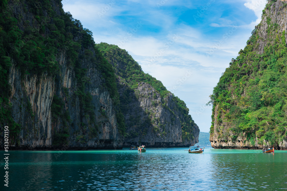 Limestone rocks, clear turquoise water, longtail boats in the Pileh Lagoon, Phi Phi, Thailand.