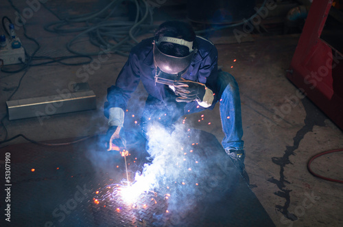  welding steel up smoke and light. Workers wearing industrial uniforms and welding masks at a welding factory protect from welding sparks. Occupational safety concept