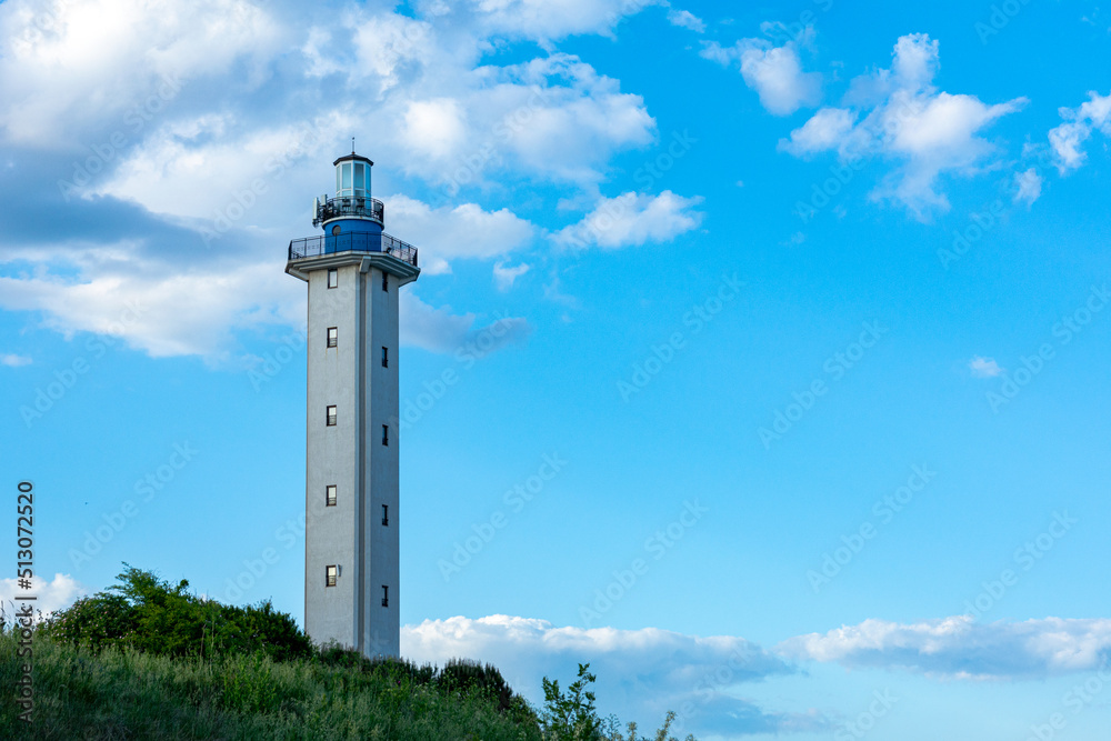 A beautiful sea lighthouse against a blue sky with clouds
