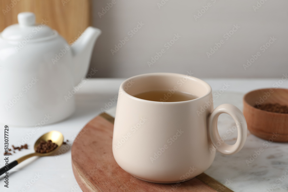Cup of aromatic buckwheat tea and granules on white table Cup of aromatic buckwheat tea and granules on white table