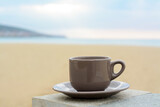 Ceramic cup of hot drink on stone surface near sea in morning, space for text