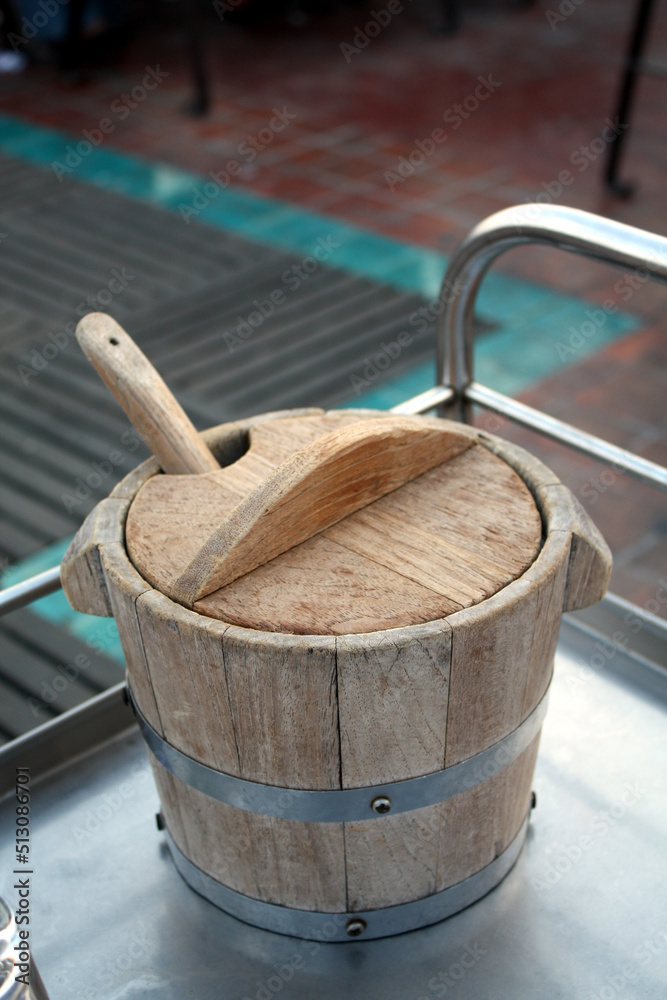 Old wooden bucket for ice on the stainless steel table in the restaurant. Selective focus.