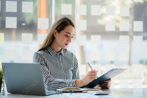 young businesswoman looking at financial data from laptop She is analyzing, calculating, examining the financial documents of a start-up woman. financial management concept