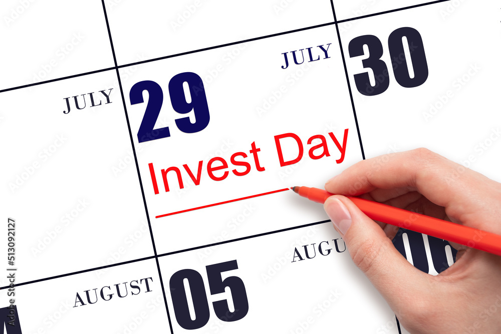 Hand drawing red line and writing the text Invest Day on calendar date July 29. Business and financial concept.