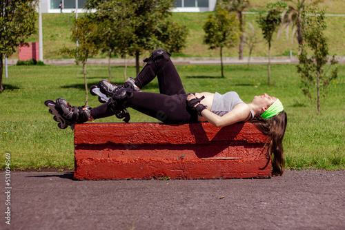 Sporty young woman stretching and resting after skating in a park on a sunny day