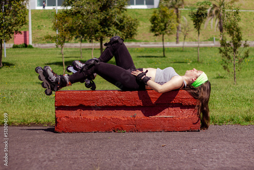 Sporty young woman stretching and resting after skating in a park on a sunny day