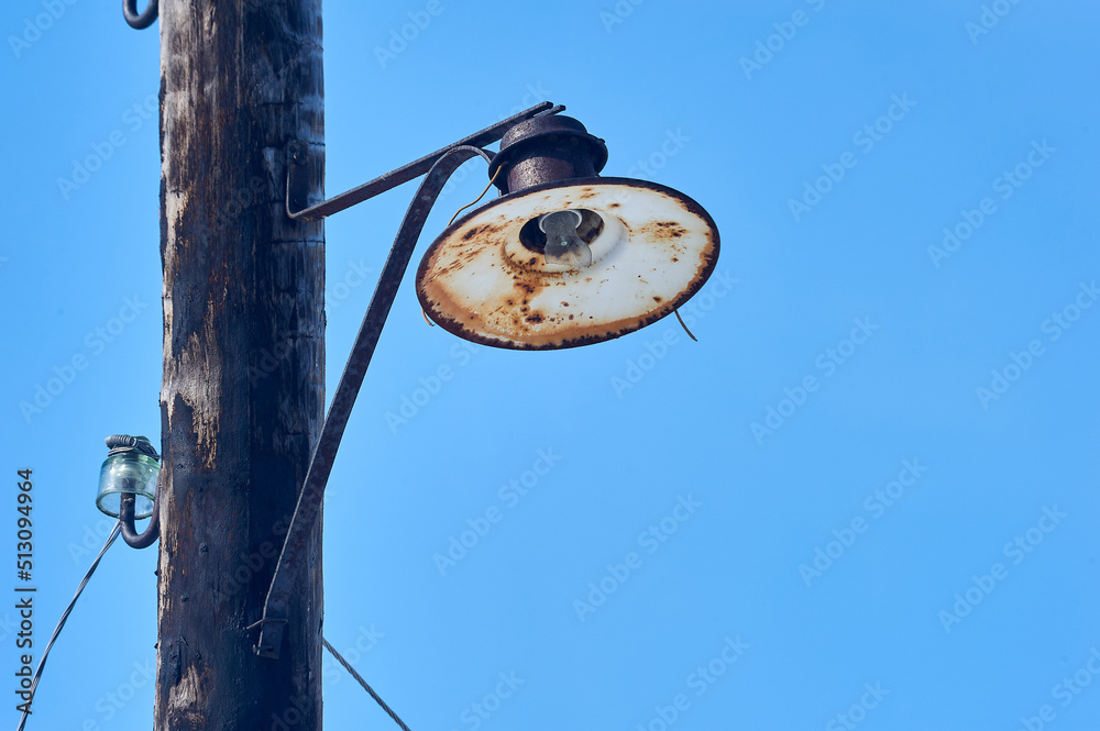 Fototapeta premium an old lantern is hanging on a wooden pole with a broken light bulb