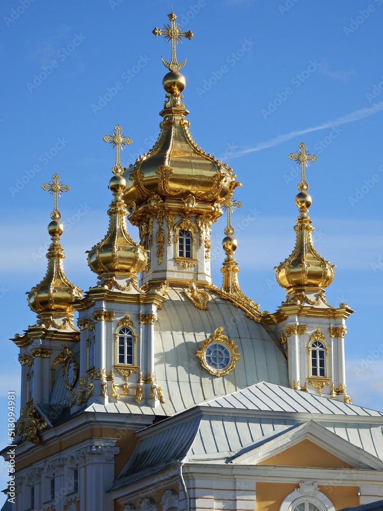 The cross atop the golden-yellow dome of a Russian building.