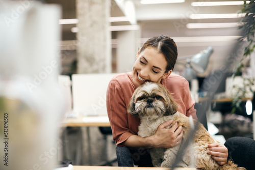 Happy businesswoman cuddling her dog while working in pet friendly office. photo