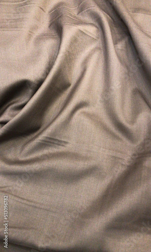The close-up texture of fabric or cloth in brown color. Fabric texture of cotton or linen textile material. Shiny brown canvas portrait background at the textile fabric store.