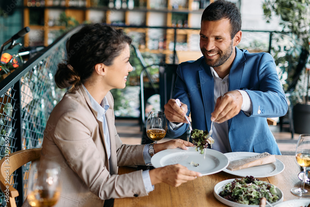 Happy businessman and his female colleague have lunch together in restaurant.
