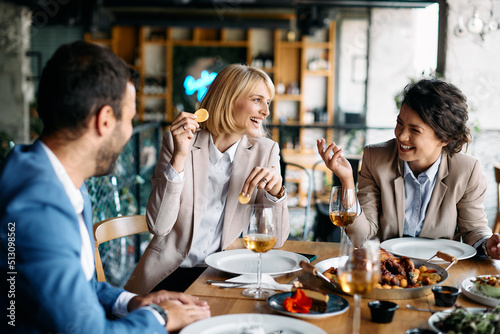 Cheerful colleagues laugh and have fun during business lunch in restaurant.