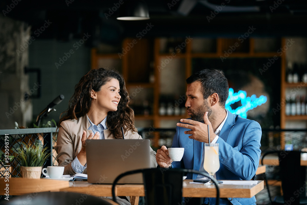 Happy business couple talks while drinking coffee on meeting in cafe.