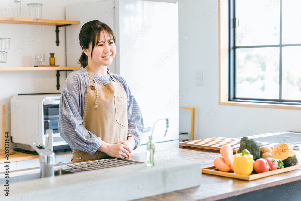 キッチンに立つエプロン姿の日本人女性
キッチンに立つエプロン姿の日本人女性