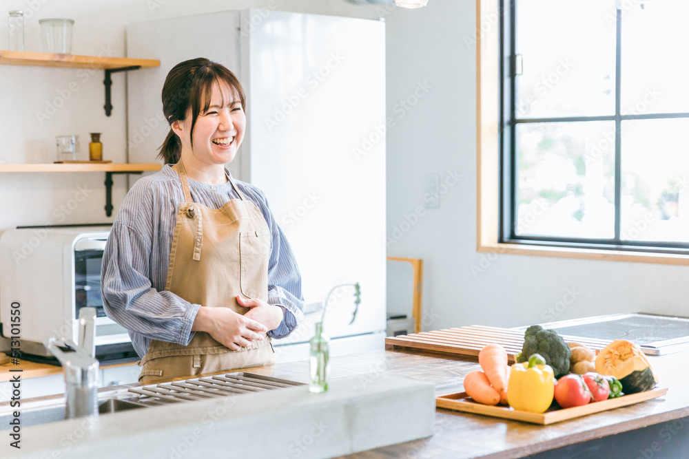 キッチンに立つエプロン姿の日本人女性
