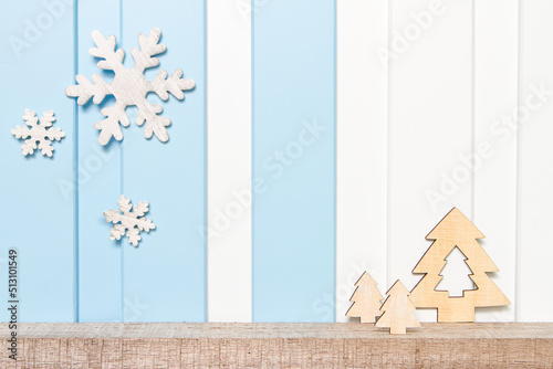 Winter decorations - Front view of wooden snow flake and pines on shelf over blue white wall background .