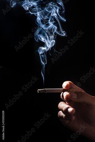 close up of man hand holding cigarette on black background