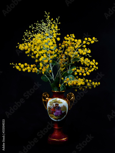 Wattle blossom in a picturescque ceramic vase on black. photo