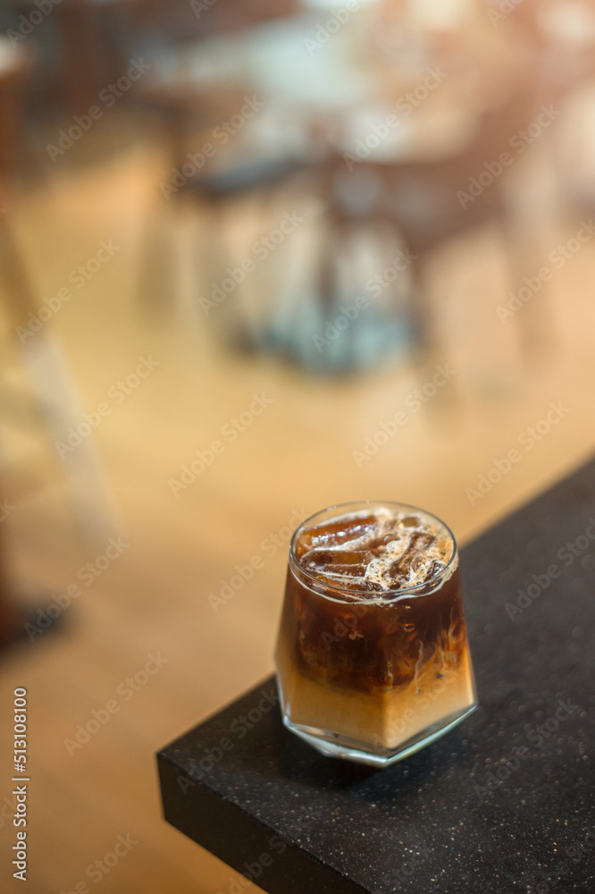 Ice coffee on a table with cream being poured into it showing the texture and refreshing look of the drink Ice coffee on a table with cream being poured into it showing the texture and refreshing look of the drink