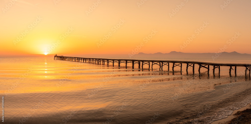 Wooden pier in the beach. Wood bridge in the beach. Sunset in the beach, golden hour. Mallorca island, 