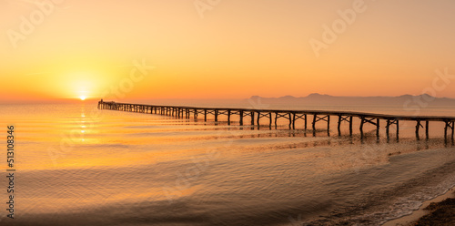 Wooden pier in the beach. Wood bridge in the beach. Sunset in the beach  golden hour. Mallorca island   Muro  beach. Mediterranean sea  Spain.