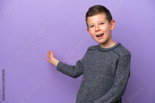 Little boy isolated on purple background extending hands to the side for inviting to come