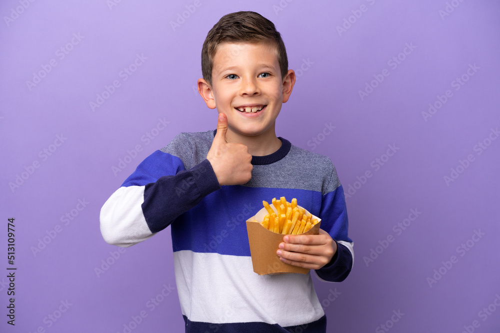 Little boy holding fried chips isolated on purple background giving a thumbs up gesture Little boy holding fried chips isolated on purple background giving a thumbs up gesture