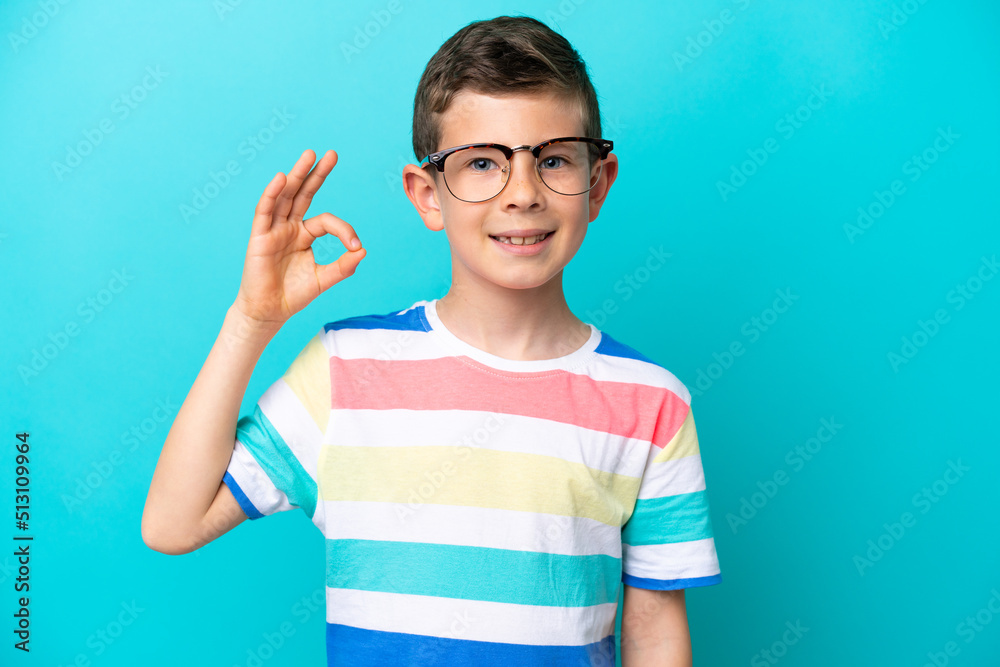 Little boy isolated on blue background With glasses and doing OK sign Little boy isolated on blue background With glasses and doing OK sign