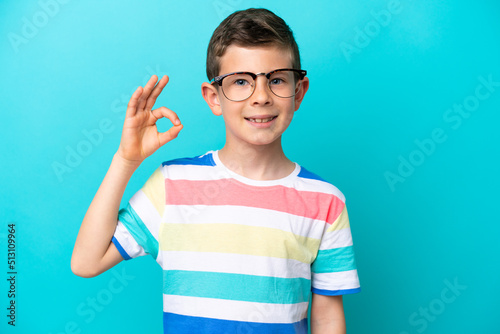 Little boy isolated on blue background With glasses and doing OK sign
