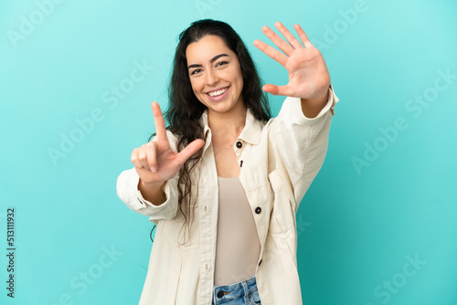 Young caucasian woman isolated on blue background counting seven with fingers