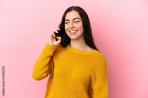 Young caucasian woman using mobile phone isolated on pink background looking to the side and smiling