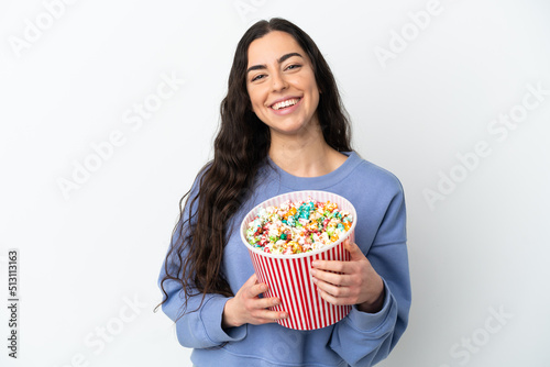 Young caucasian woman isolated on white background holding a big bucket of popcorns