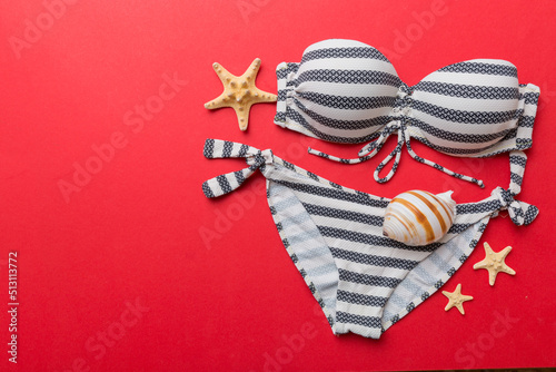 Woman swimwear and beach accessories flat lay top view on colored background Summer travel concept. bikini swimsuit, straw hat and seasheels. Copy space Top view